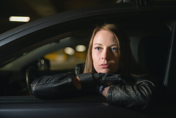 Young woman driver is looking through the car window at night.
