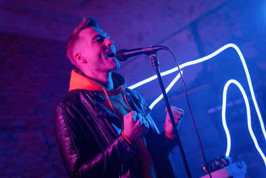 A man singer with the microphone in the neon lights concept.