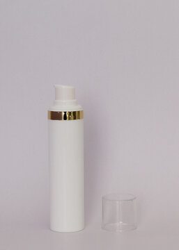 Envase tubular de plastico en color blanco con tapa transparente y franja en color dorado. 