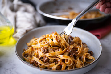 lifting up fettuccine ragu with fork