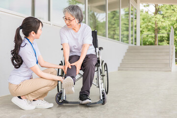 車椅子に乗る高齢者と介護士（ふくらはぎ・足首）
