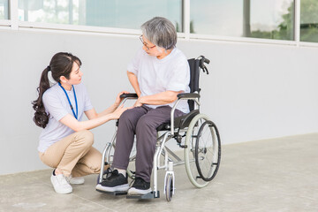 Fototapeta na wymiar 車椅子に乗る高齢者と介護士（股関節） 