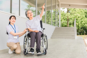 車椅子に乗る高齢者と介護士（ヘルパー）
