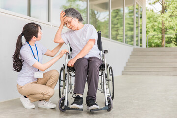 Fototapeta na wymiar 車椅子に乗る高齢者と介護士（頭痛・発熱） 