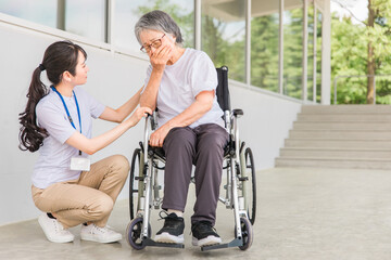 介護士と咳をする車椅子に乗った高齢者
