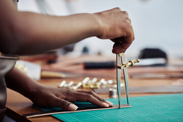 Side view closeup of black female artisan measuring leather piece in leatherworking shop, copy space