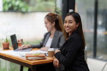 Positive Asian secretary smiling to camera during meeting at office