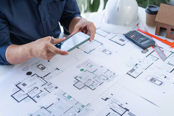Close up man hand working of Architect blueprint at desk in construction work.