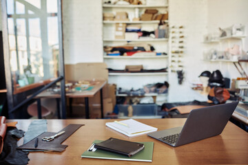 Background image of table with computer in leatherworking shop, copy space