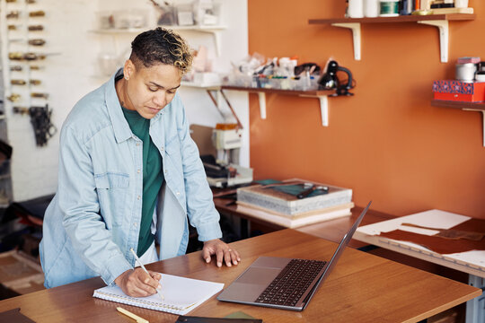 Portrait of black woman writing in planner while managing small business manufactory, copy space