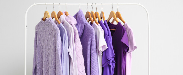 Hanger with clothes in purple shades on light background