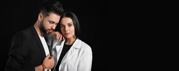 Stylish young couple with dark hair on black background with space for text