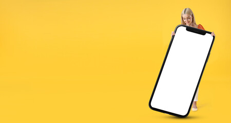 Beautiful young woman and big smartphone on yellow background with space for text