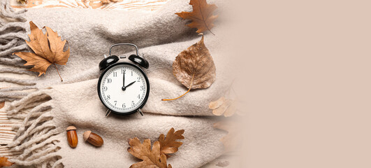 Alarm clock and autumn leaves on scarf. Banner for design