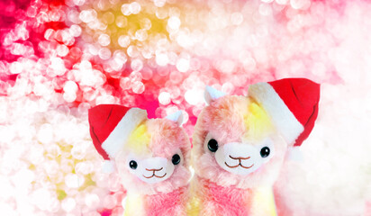 Fluffy funny couple llamas , soft stuffed toys alpacas in Santa hats on festive bright shiny bokeh ...