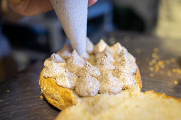A baker fills brioche cream in a craft bakery. A close-up photo. Front view.