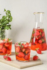 Board with glasses of strawberry lemonade on white background