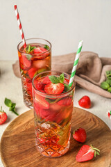 Wooden board with glass of strawberry lemonade on white background