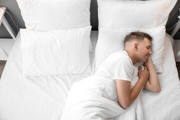 Handsome young man sleeping in bed at home