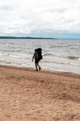 One person with a backpack walks along the seashore.