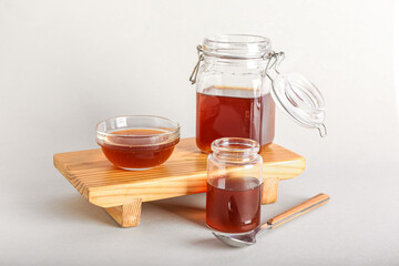 Wooden board with jars and bowl of tasty maple syrup on white background - obrazy, fototapety, plakaty