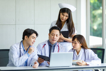 Group of Asian successful professional male and female doctors in white lab coat uniform with stethoscope and nurse sitting meeting discussing together holding human skeleton model in hospital office