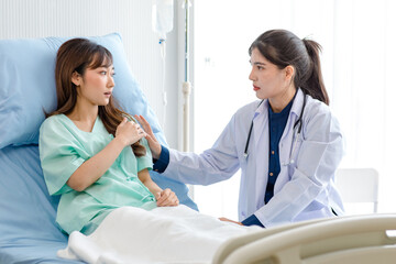Obraz premium Asian young professional female practitioner doctor in white lab coat with stethoscope holding touching checking monitoring patient injury arm and muscle while laying down on bed in hospital wardroom
