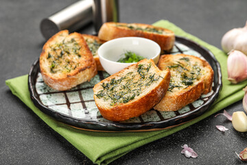 Plate with slices of toasted garlic bread on dark background, closeup