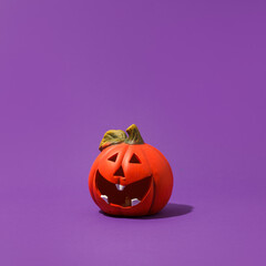 Jack-o-lantern, pumpkin toy for Halloween on purple background. Plastic pumpkin, trick or treat, seasonal celebration. Traditional autumn holiday decor, Copy space, banner