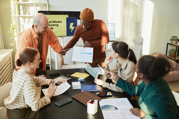 Fototapeta premium Portrait of creative business team meeting in office with focus on black man presenting marketing data