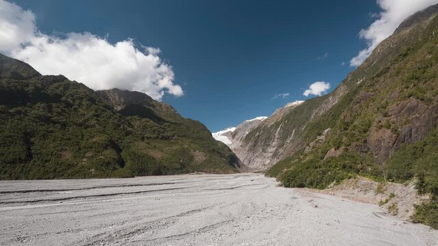 View up the Waiho River valley towards the Franz Josef glacier, West Coast, South Island, New Zealand. Clouds forming and dissipating over the mountains.
