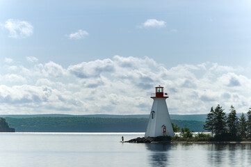 Sunrise view of lighthouse on Bras D'Or lake near Baddeck, Nova Scotia Canada. Silhouette of a...
