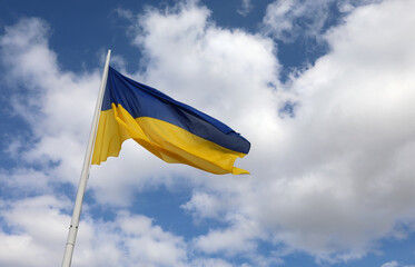 ukrainian flag flying with the background of blue sky and white clouds