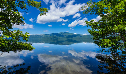 Fototapeta na wymiar 白い雲の浮かぶ鮮やかな青空を湖面に反射する湖。