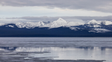 Obraz na płótnie Canvas View of a frozen Yellowstone Lake with snow covered mountains in American Landscape. Yellowstone National Park. United States. Nature Background.