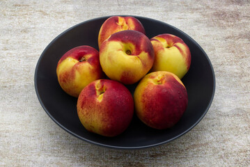 Peaches in a black dish isolated on a rustic table