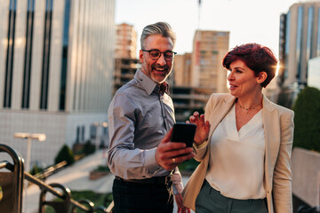 Urban businessman and businesswoman with smartphone outdoors