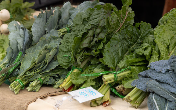 Organic Grown Green Vegetables And Dark Leafy Food Chard Stacked On A Table For Sale At Farmers Market