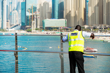 Rear view of a male security guard looking at the skyline of a modern city