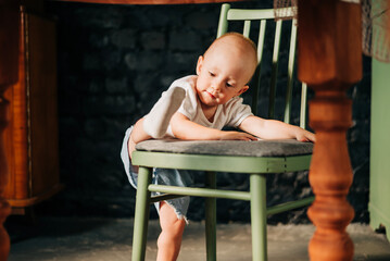 Little baby girl climbing high-chair child climbs chair