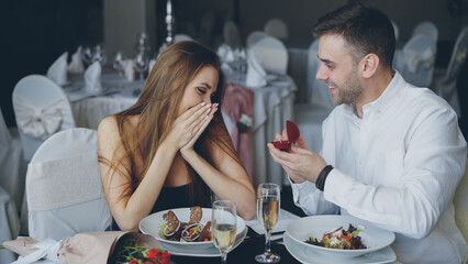 Attractive young woman is saying yes to marriage proposal. Romantic relationship and restaurant...