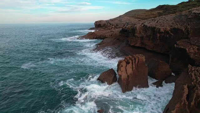 panoramic view of waves breaking hard on the cantabrian coast with natural colors in Isla, a village of Cantabria, Spain. Drone panning shoot.