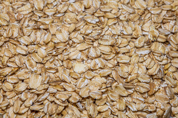 A close-up of raw rolled oats, showcasing their texture and color, ready to be used in cooking or baking.