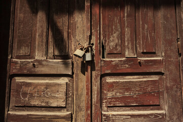 two dusted old padlocks on a wooden old door
