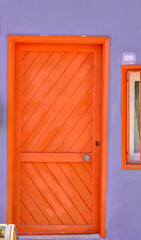 Colorful door and wall. Purple color wall and orange color door. Cute house concept idea.