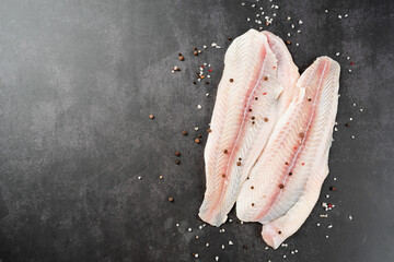 Raw pangasius fish fillet with spice on concrete background