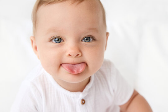 Close up of cute blue-eyed baby sticking out tongue