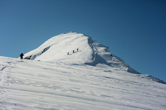 Mountain climbers climbing sunny, snowy mountain peak, Selkirk Mountains, Canada
