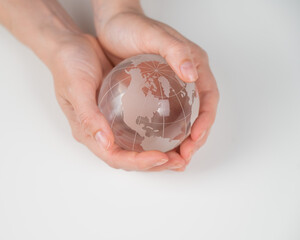 Crystal globe in female hands on a white background. 