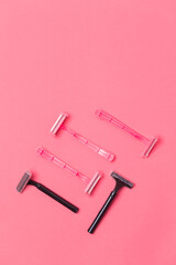 Female Shaving Concepts. Flat-Lay Image of Various Women's Colorful Pink and Black  Disposable Razors Shavers Placed in Different Directions On Pink Coral Background